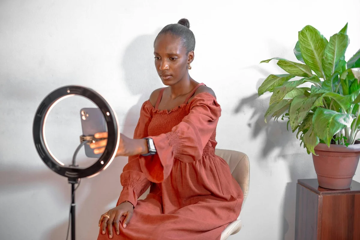 Cómo elegir el formato de contenido correcto en TikTok: tuto... — A young woman uses a smartphone ring light setup for vlogging from home.