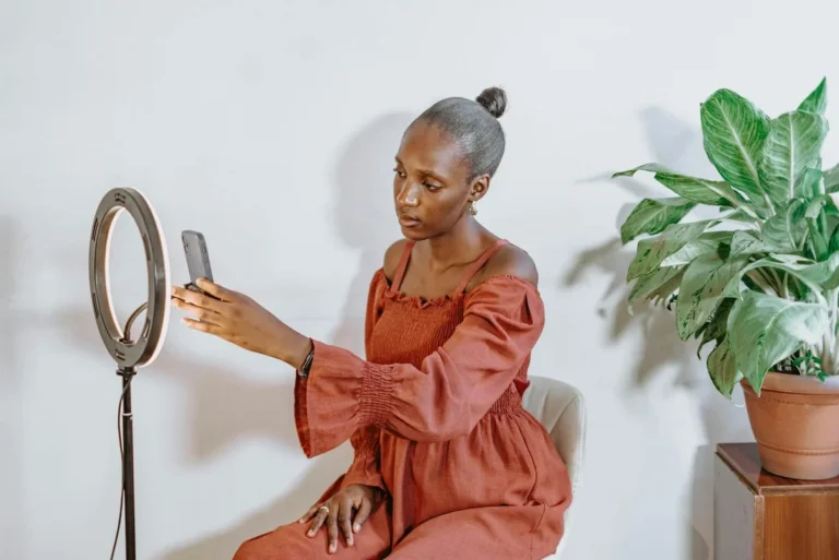 How to Find Your TikTok Niche in 2026: Step-by-Step Tutorial — Young African woman using a ring light and smartphone to vlog indoors with a pot