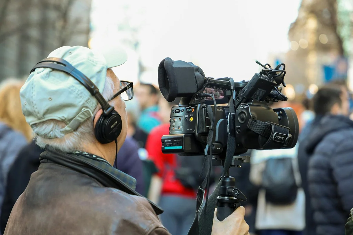 Cómo mantener la constancia en TikTok sin quemarte: tutorial... — A cameraman records an urban event with professional equipment in a bustling cit