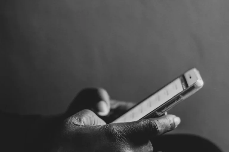 How to Make the TikTok Algorithm Work for You in 2026: Step-... — A monochrome image showing a person using a smartphone, emphasizing modern techn