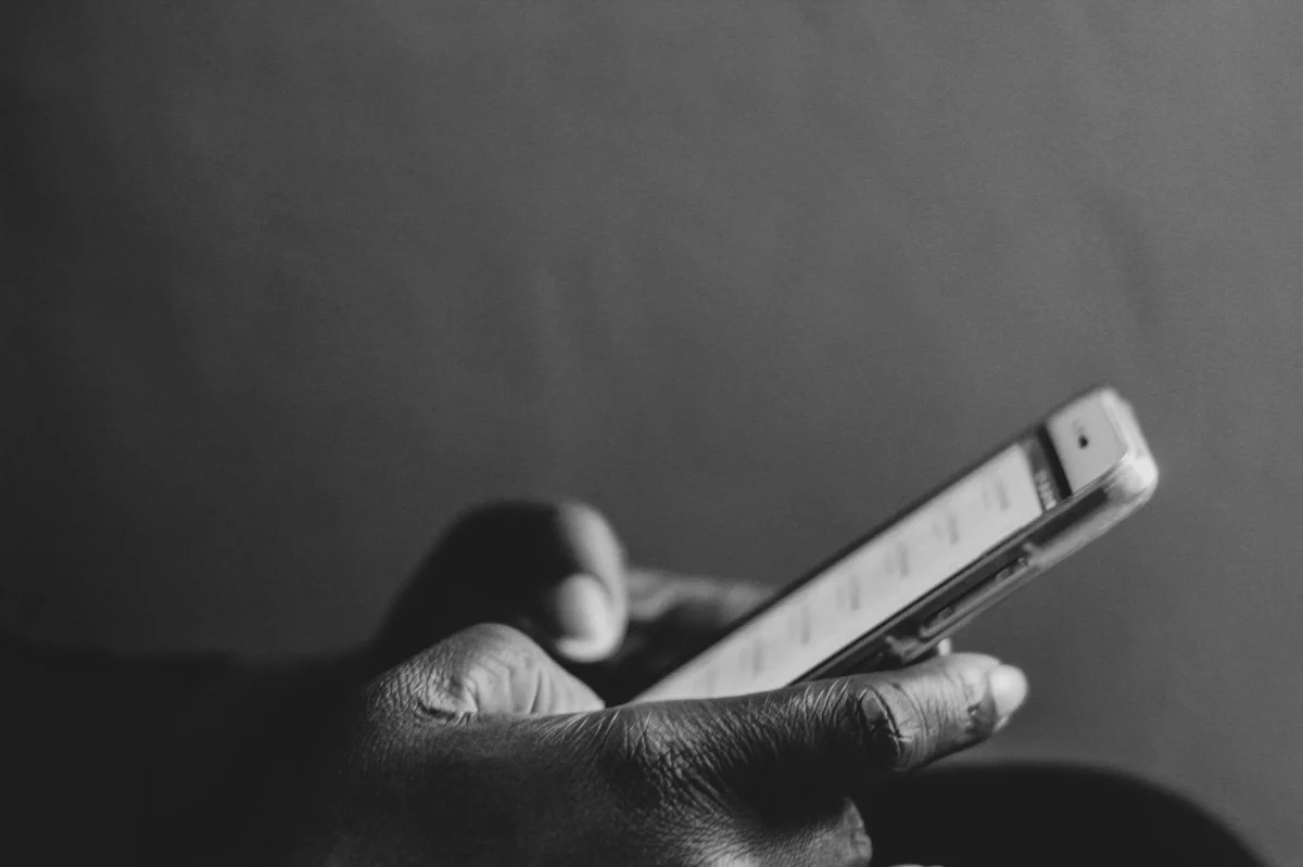 How to Make the TikTok Algorithm Work for You in 2026: Step-... — A monochrome image showing a person using a smartphone, emphasizing modern techn