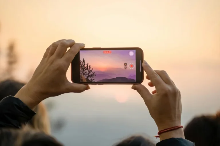 How to Turn Your TikTok Knowledge Into Products and Services — A person capturing a breathtaking sunset on a smartphone, highlighting the blend