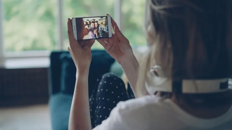 Cómo construir comunidad en TikTok: tutorial paso a paso — Woman sitting on couch, capturing selfie with phone indoors, wearing headphones.