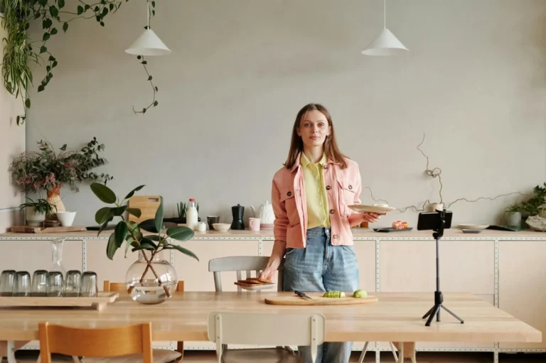 How to Read TikTok Analytics Like a Pro: Step-by-Step Tutori... — Young woman in kitchen setting up a cooking vlog with smartphone on tripod.