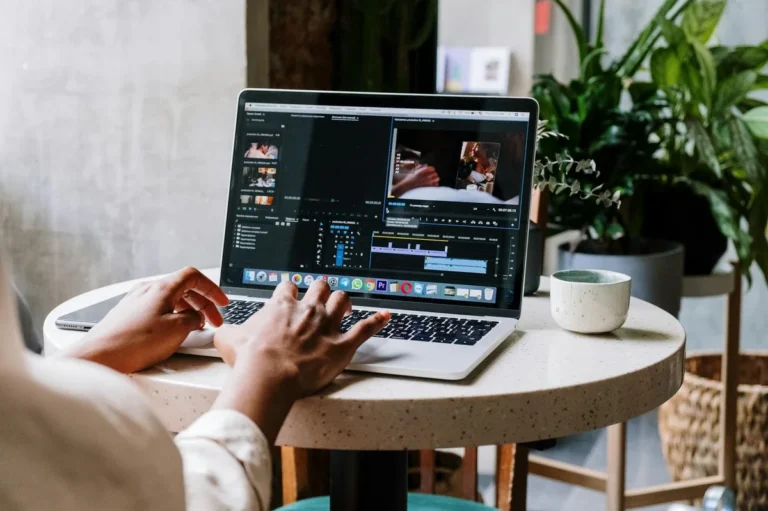 Cómo conseguir y gestionar colaboraciones con marcas en TikT... — Freelance video editor working on a laptop in a cafe setting, utilizing Adobe so