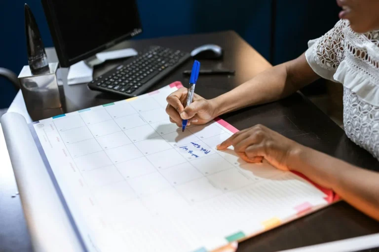 Enfoque Real: como eliminar las distracciones que te estan r — Person writing important notes in a desk calendar with a pen, set in an office.
