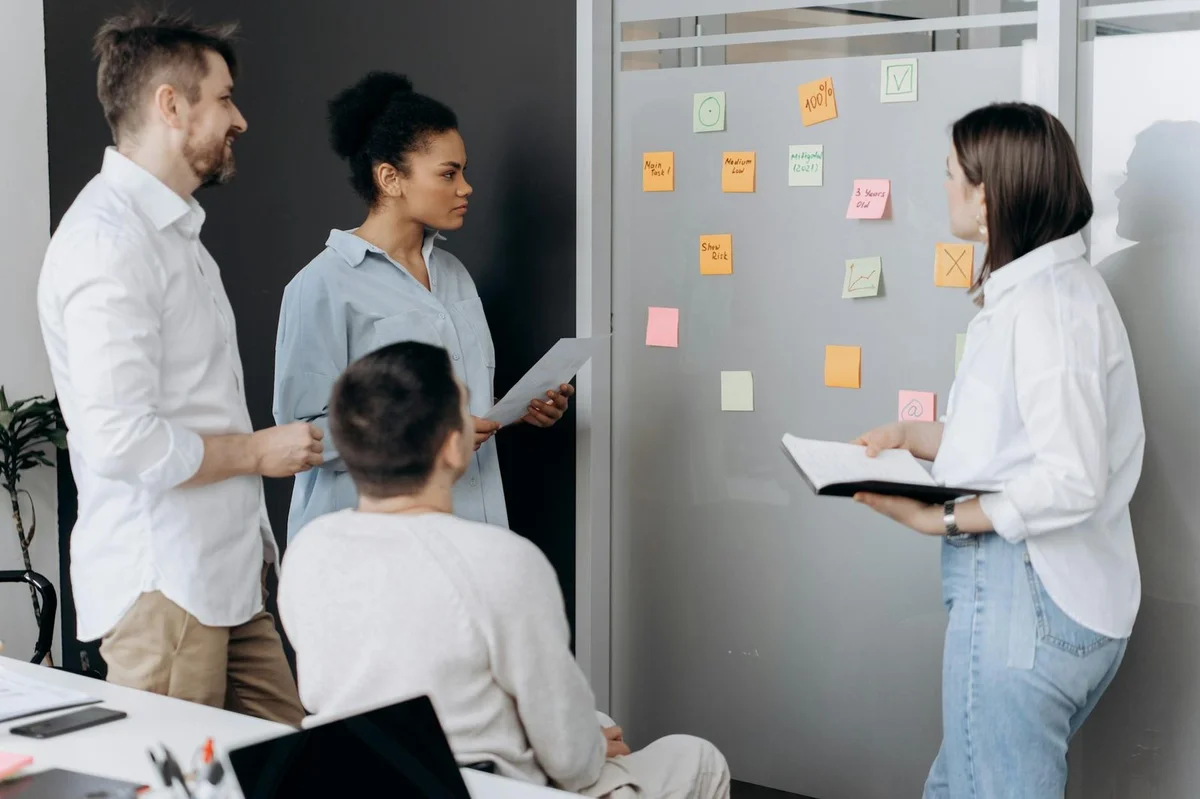Cómo descomponer decisiones complejas con IA: tutorial de lo... — Diverse team collaborating in an office, discussing ideas using sticky notes and