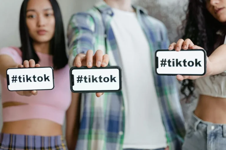Cómo entender TikTok por dentro: tutorial completo de la pla... — Young adults holding smartphones with TikTok hashtag, showcasing social media en