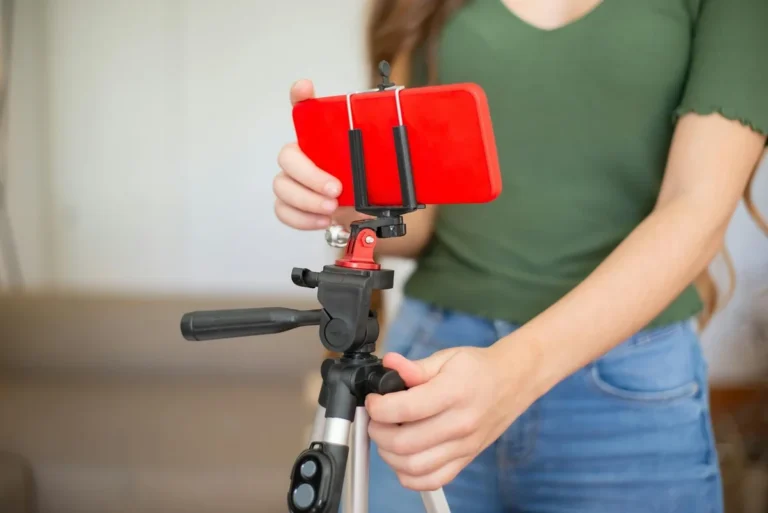 How to Make Money on TikTok: Income Streams Step-by-Step — Female adjusting smartphone onto tripod for recording indoors.