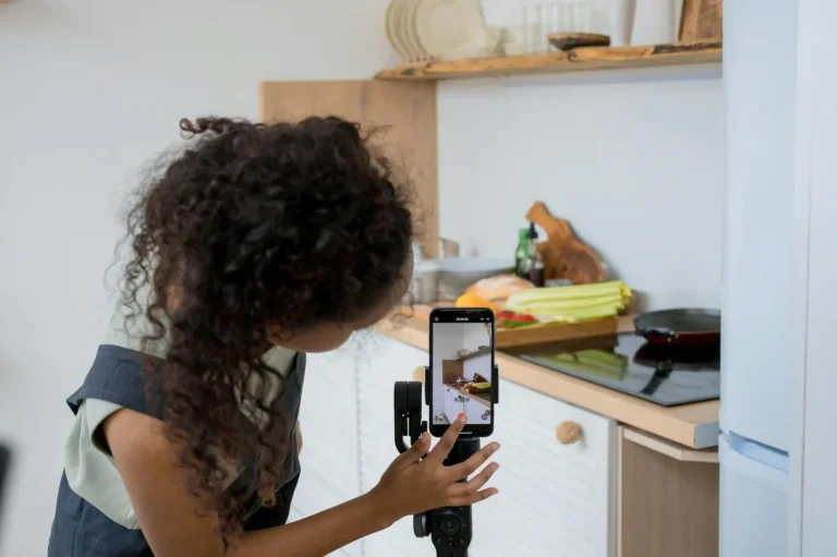 Cómo automatizar tu contenido en TikTok: tutorial de sistema... — A woman with curly hair films a cooking video using a smartphone stabilizer in a