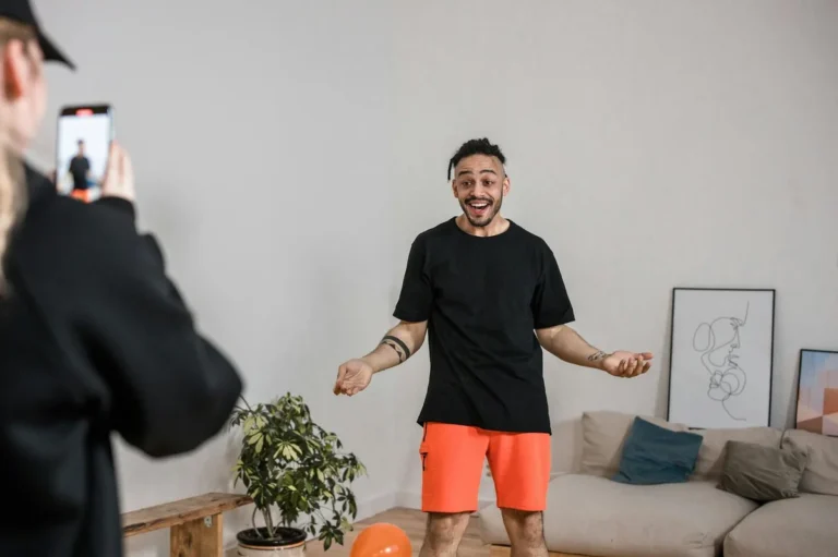 How to Start Creating TikTok Content with What You Already H... — Man in black shirt vlogging indoors with smartphone capturing lively expressions