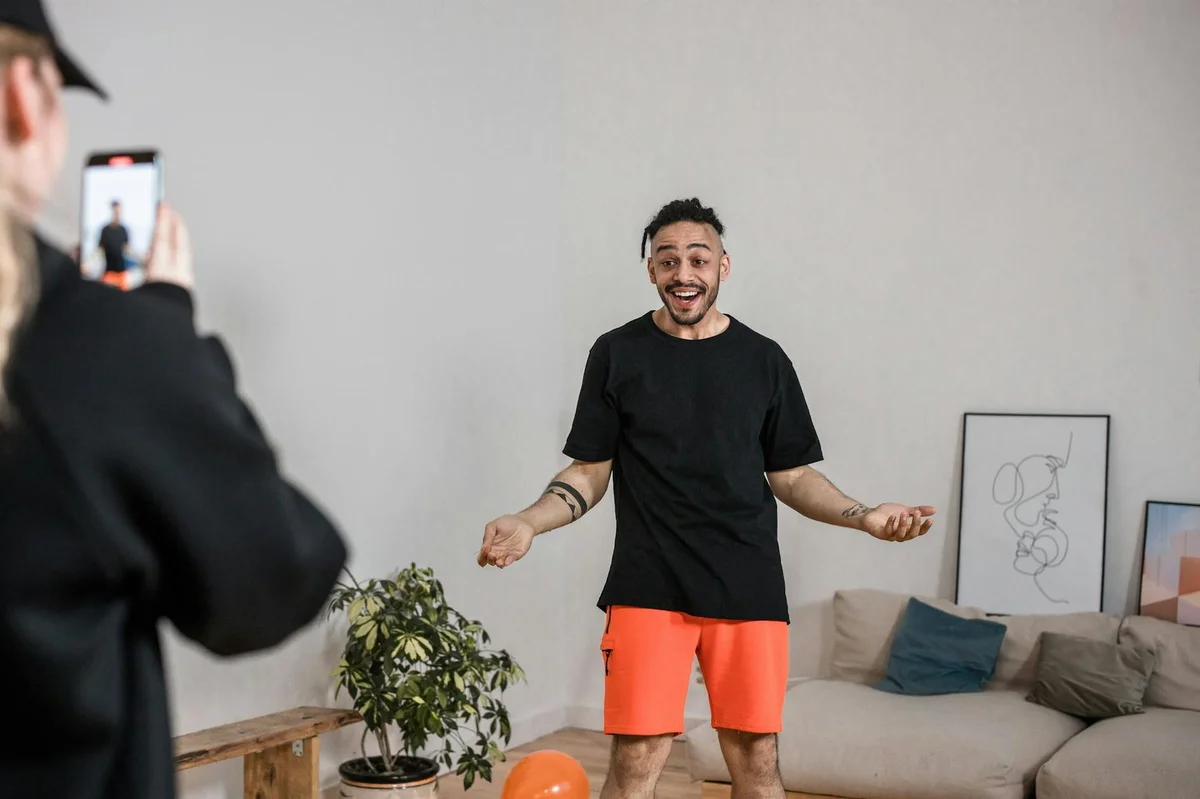 How to Start Creating TikTok Content with What You Already H... — Man in black shirt vlogging indoors with smartphone capturing lively expressions