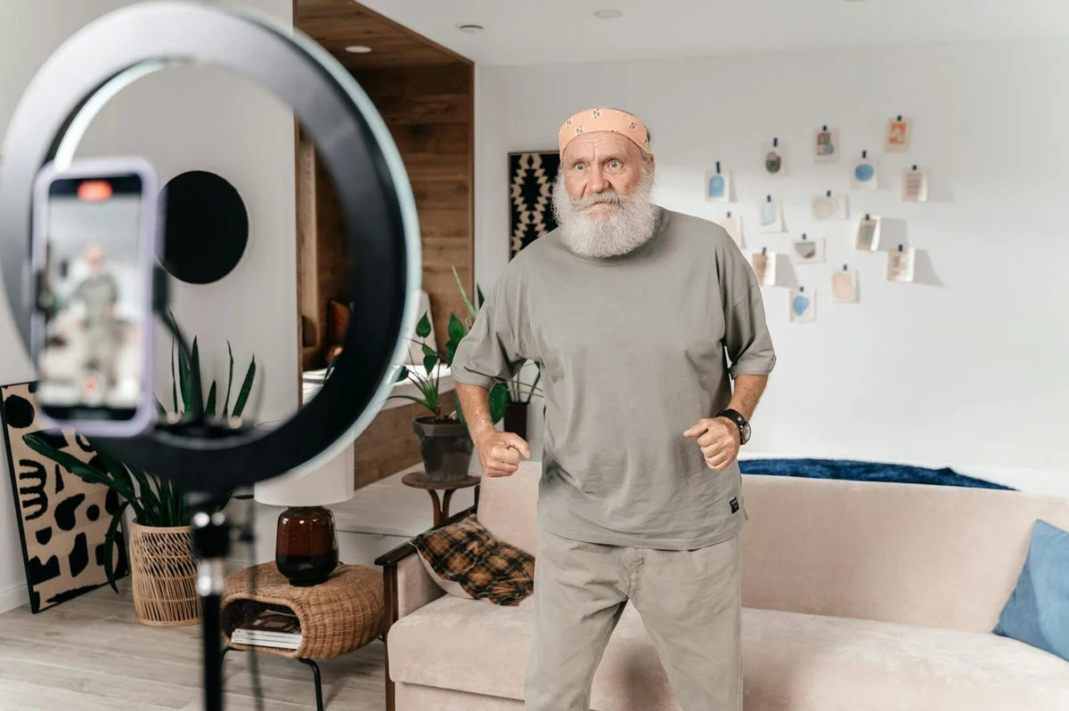 How to Script TikTok Videos Without Sounding Scripted: Step-... — Senior man dances for a social media video using a phone and ring light setup in