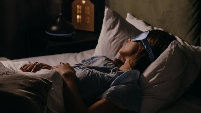 Apaga tu mente: cuando el ruido mental no te deja ni dormir - A woman peacefully sleeping with an eye mask in a dimly lit bedroom, capturing a