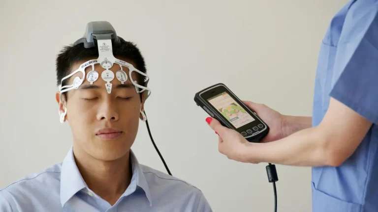 Healthcare professional conducting an EEG examination using a Brainscope device on a male patient.