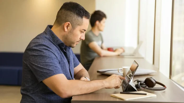 Two men working on devices in a modern office setting, emphasizing technology and collaboration.