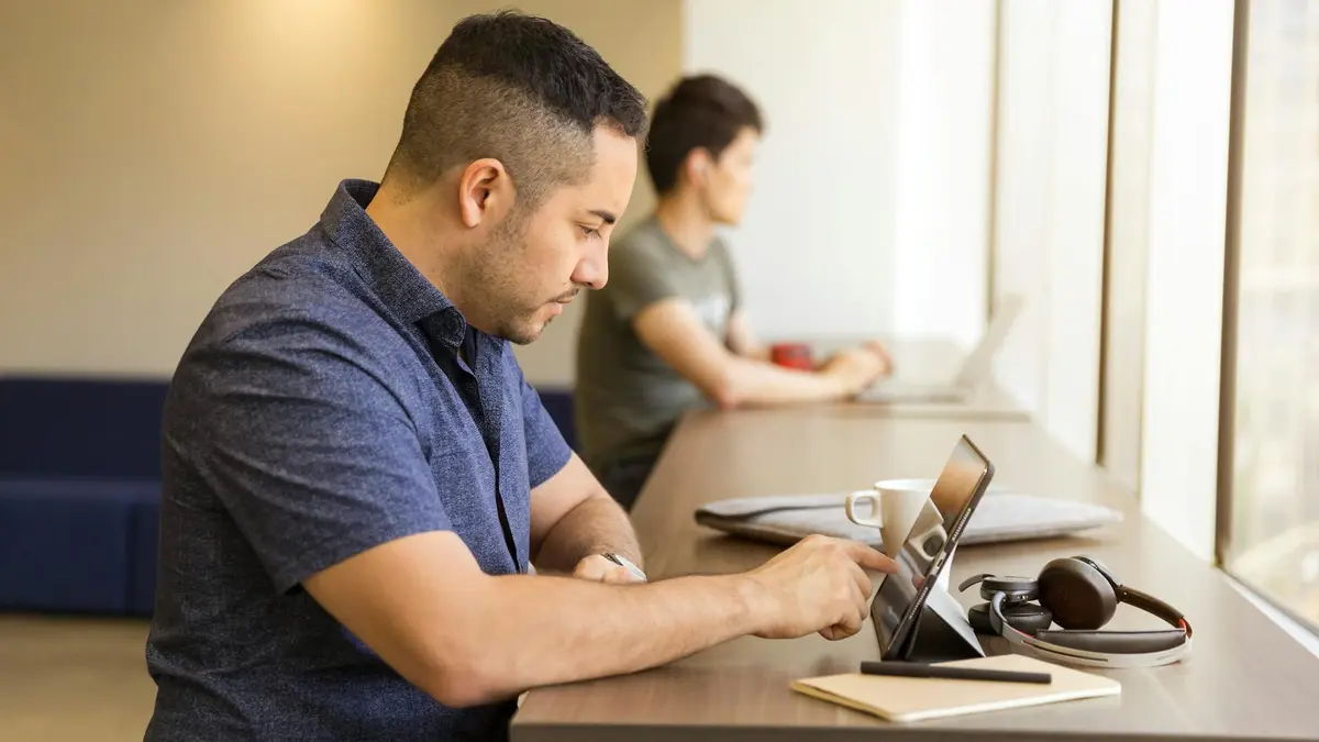 Two men working on devices in a modern office setting, emphasizing technology and collaboration.