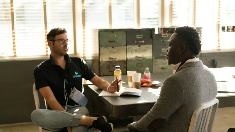 Two men having a focused business discussion in a sunlit office space.